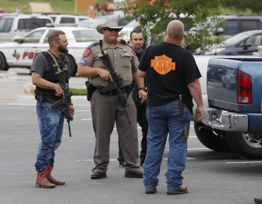 Law enforcement officers talk to a man near the parking lot of a Twin Peaks Restaurant Sunday, May 17, 2015, in Waco, Texas, after a shooting involving rival biker gangs. Waco police Sgt. W. Patrick Swanton told KWTX-TV there were ?multiple victims? after gunfire erupted between the gang members. (Rod Aydelotte/Waco Tribune Herald via AP)