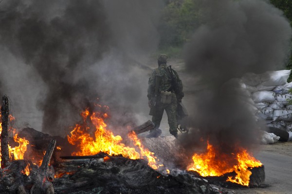 A pro-Russian separatist guards a checkpoint while walking near burning tyres near the town of Slaviansk in eastern Ukraine May 2, 2014. Ukraine launched a "large-scale operation" to retake the eastern town of Slaviansk, pro-Russian separatists there said on Friday, in an escalation of violence in what has become the worst confrontation between Russia and the West since the Cold War. REUTERS/Baz Ratner (UKRAINE - Tags: POLITICS CIVIL UNREST)