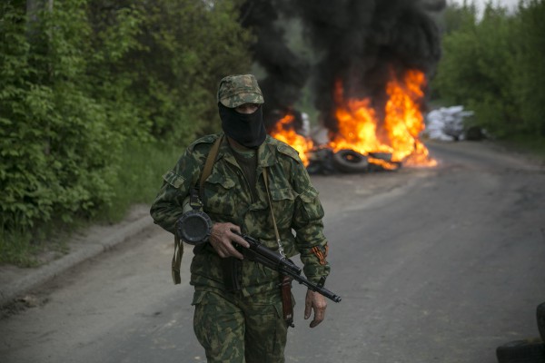 A pro-Russian separatist guards a checkpoint as tyres burn behind him near the town of Slaviansk in eastern Ukraine May 2, 2014. Ukraine launched a "large-scale operation" to retake the eastern town of Slaviansk, pro-Russian separatists there said on Friday, in an escalation of violence in what has become the worst confrontation between Russia and the West since the Cold War. REUTERS/Baz Ratner (UKRAINE - Tags: POLITICS CIVIL UNREST TPX IMAGES OF THE DAY)